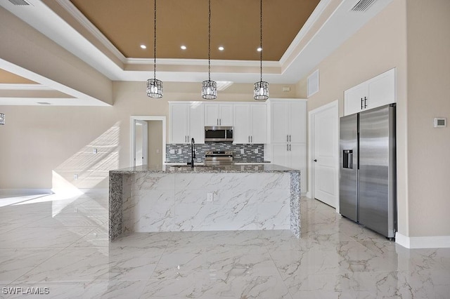 kitchen with white cabinets, decorative light fixtures, stainless steel appliances, and dark stone counters