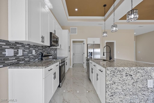 kitchen with a center island with sink, sink, appliances with stainless steel finishes, decorative light fixtures, and white cabinetry