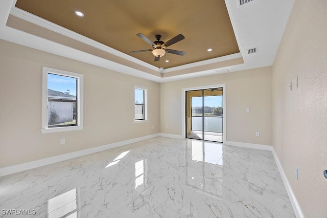 unfurnished room with a tray ceiling, crown molding, ceiling fan, and a healthy amount of sunlight