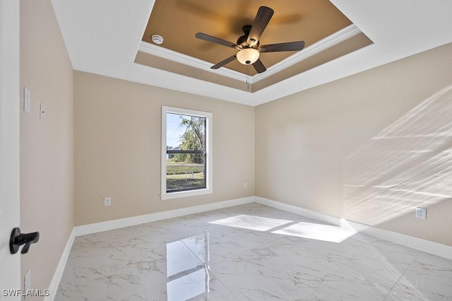 empty room with ceiling fan, a raised ceiling, and crown molding