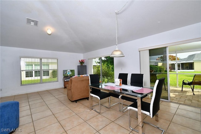 tiled dining area featuring a healthy amount of sunlight and vaulted ceiling