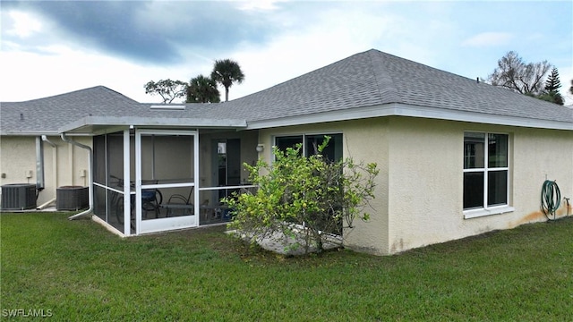 back of property with a sunroom, a yard, and central AC