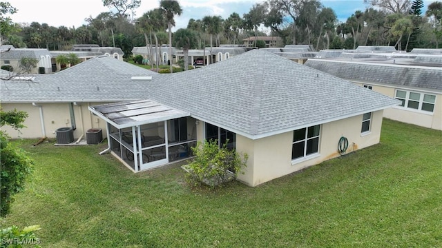 rear view of property featuring a lawn, central AC, and a sunroom