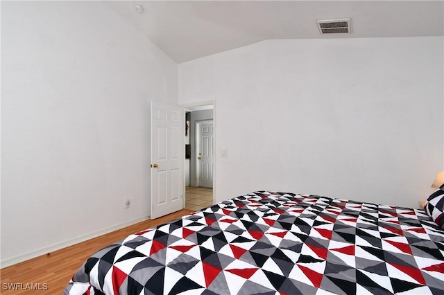 bedroom featuring lofted ceiling and light wood-type flooring