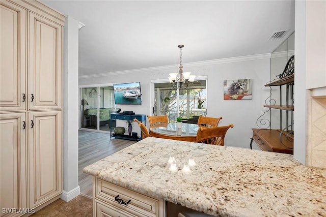 kitchen featuring light hardwood / wood-style flooring, an inviting chandelier, crown molding, and cream cabinets