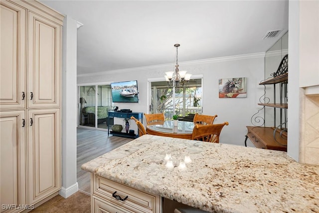 1549 Sandpiper St Unit 80, Naples, FL 34102 - kitchen with cream cabinetry, a chandelier, light stone countertops, ornamental molding, and hanging light fixtures