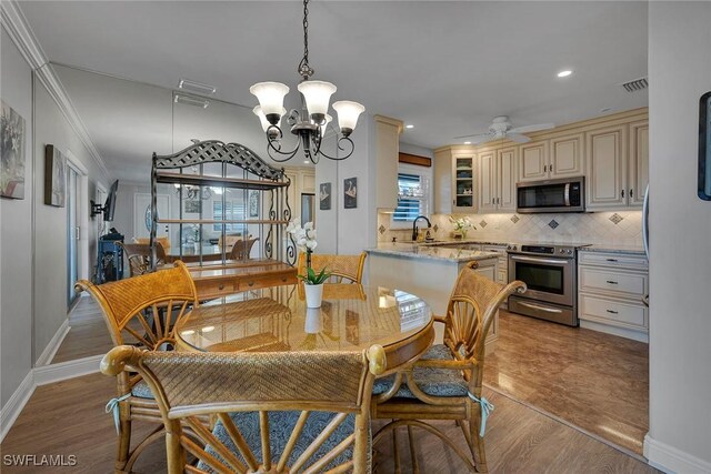 dining room featuring ceiling fan with notable chandelier, ornamental molding, sink, and light hardwood / wood-style flooring