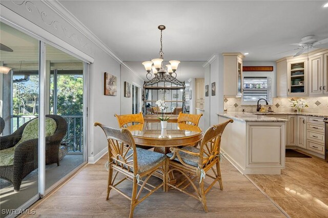 dining room with ceiling fan with notable chandelier, light hardwood / wood-style floors, ornamental molding, and sink