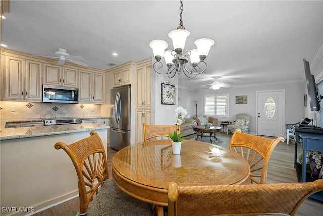 dining space featuring ceiling fan with notable chandelier, dark hardwood / wood-style floors, and ornamental molding