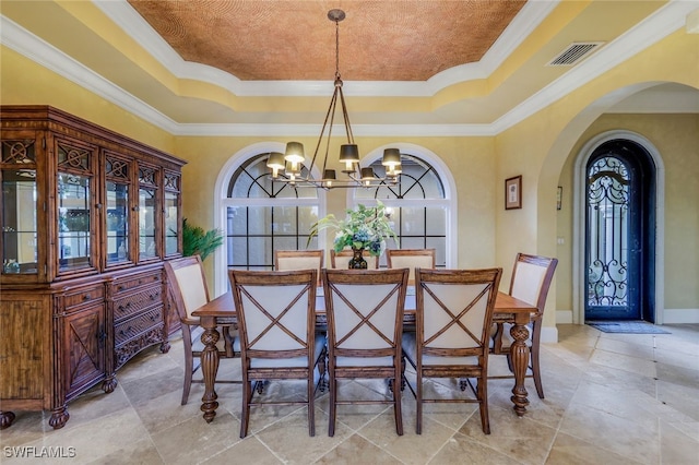 dining space with a healthy amount of sunlight, a raised ceiling, ornamental molding, and a notable chandelier