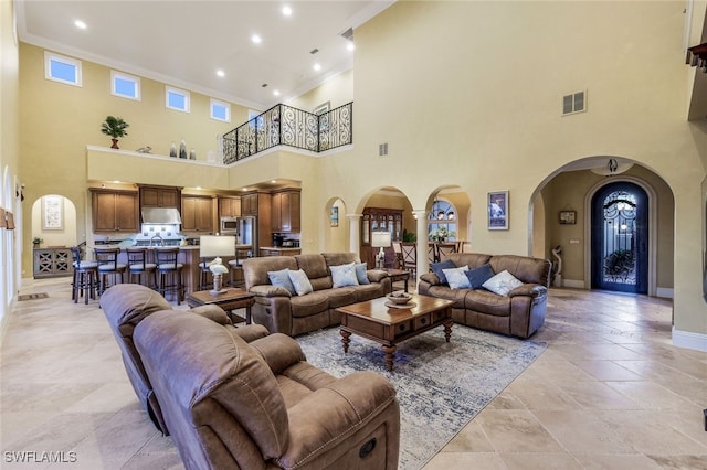 living room with a towering ceiling and crown molding