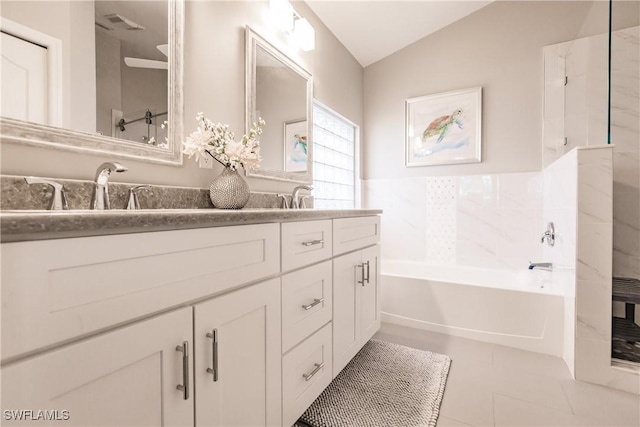 bathroom with tile patterned floors, vanity, vaulted ceiling, and a bathing tub