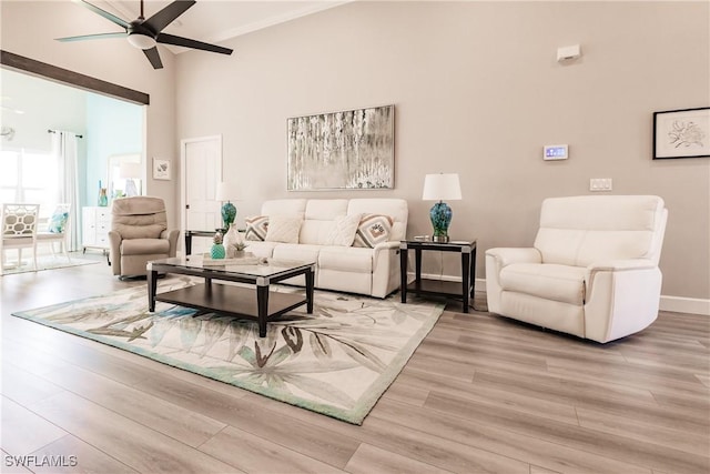 living room featuring ceiling fan, light hardwood / wood-style flooring, and a towering ceiling