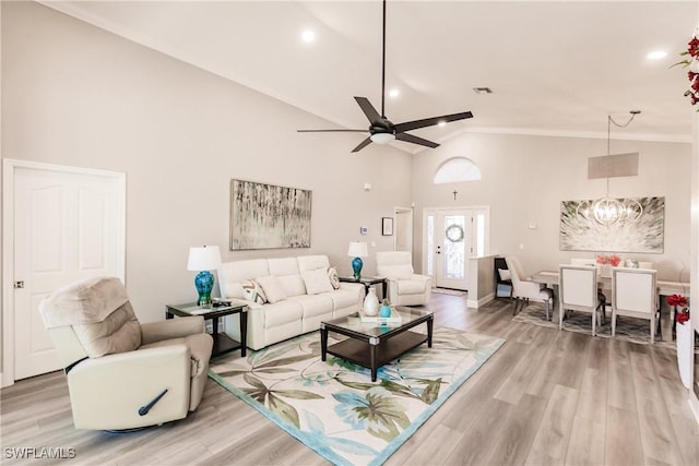 living room featuring hardwood / wood-style floors, ceiling fan with notable chandelier, high vaulted ceiling, and crown molding