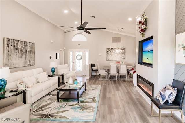 living room featuring hardwood / wood-style floors, ceiling fan, ornamental molding, and high vaulted ceiling