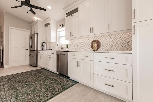 kitchen featuring backsplash, white cabinets, lofted ceiling, and appliances with stainless steel finishes