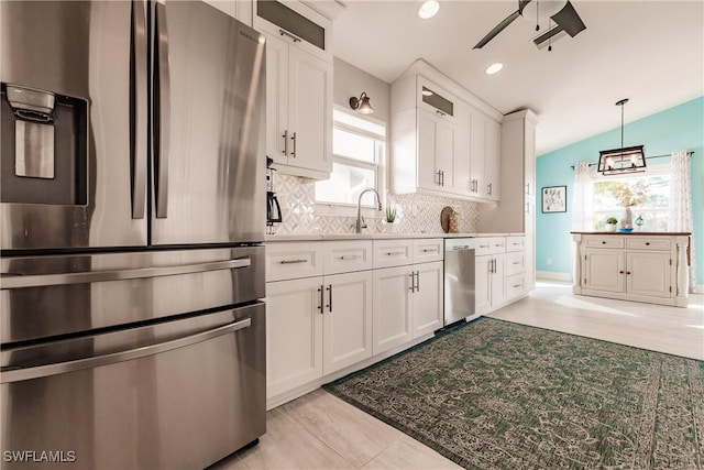 kitchen with white cabinets, vaulted ceiling, decorative backsplash, ceiling fan, and stainless steel appliances