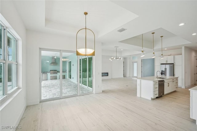 kitchen with a raised ceiling, white cabinetry, and light hardwood / wood-style flooring