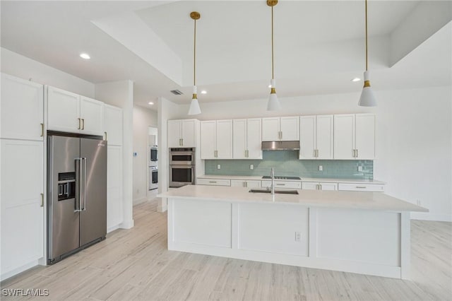 kitchen featuring a kitchen island with sink, white cabinets, hanging light fixtures, and appliances with stainless steel finishes