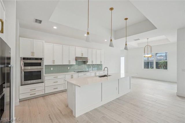 kitchen featuring decorative light fixtures, light wood-type flooring, stainless steel appliances, and sink