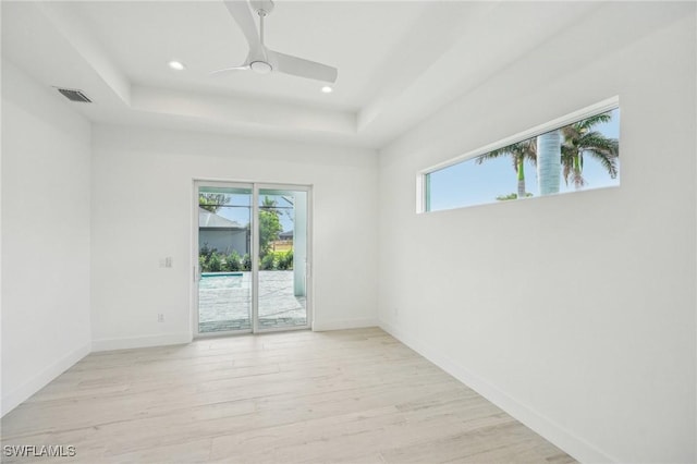 unfurnished room with a tray ceiling, light hardwood / wood-style flooring, and ceiling fan