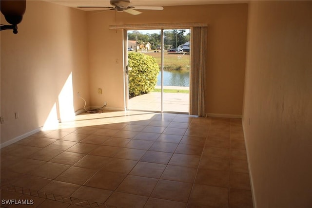 unfurnished room with a water view, tile patterned floors, and ceiling fan