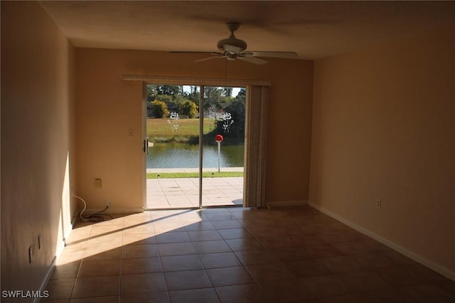 tiled empty room featuring a water view and ceiling fan