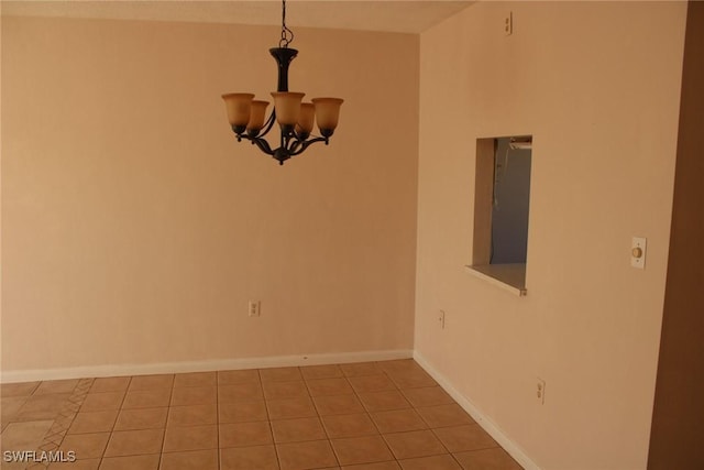 empty room with light tile patterned floors and a chandelier