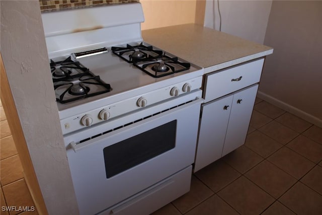 kitchen featuring tile patterned flooring, white cabinetry, and gas range gas stove