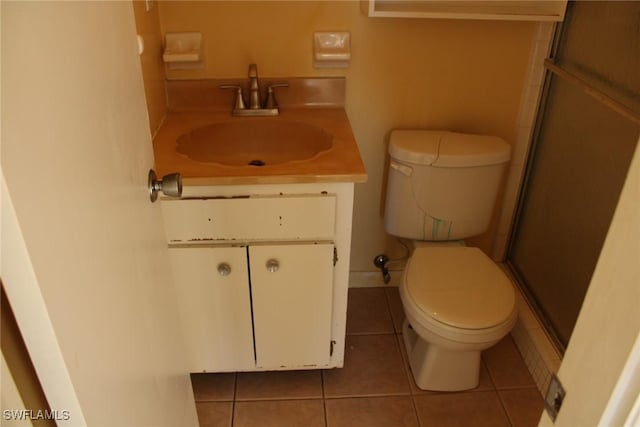 bathroom featuring tile patterned flooring, vanity, toilet, and walk in shower