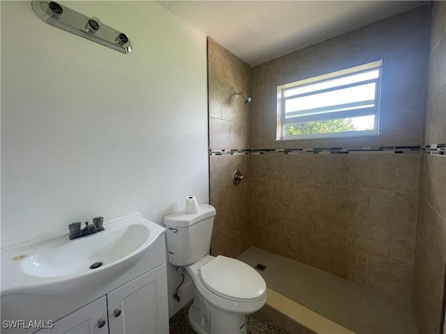 bathroom with vanity, toilet, and a tile shower