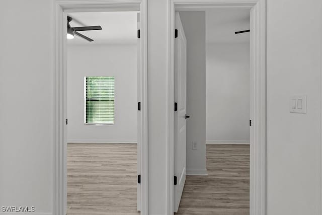 corridor featuring baseboards and wood finished floors