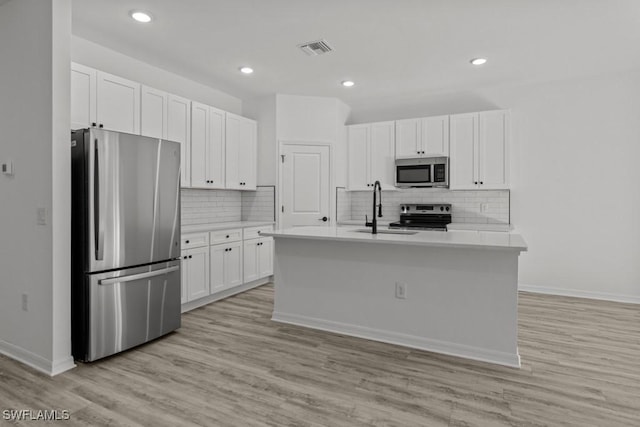 kitchen with stainless steel appliances, a sink, visible vents, white cabinetry, and light countertops