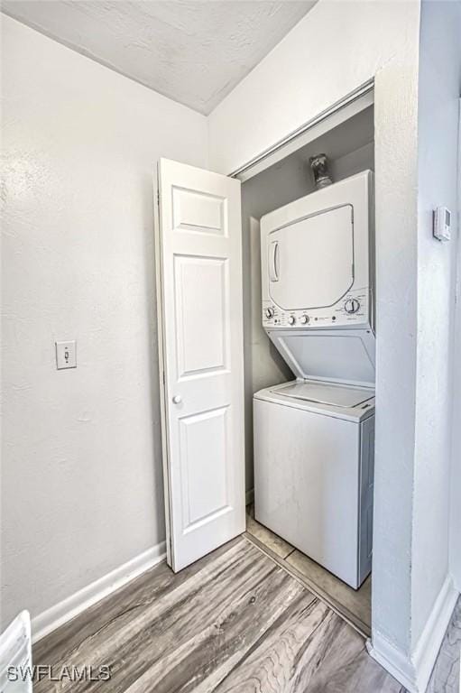 laundry area with stacked washer and dryer and wood-type flooring