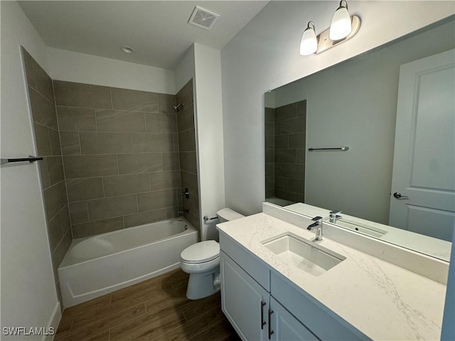 full bathroom with hardwood / wood-style floors, vanity, tiled shower / bath combo, and toilet