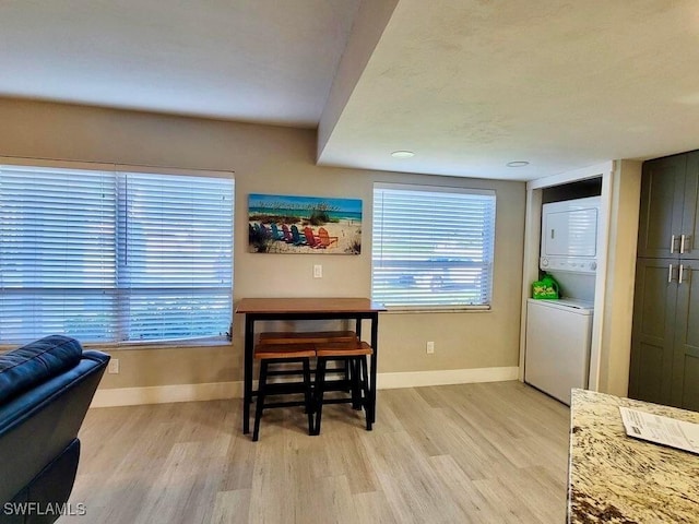 dining area with stacked washer / drying machine and light hardwood / wood-style floors