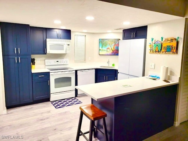 5023 SW 16th Pl Unit 101, Cape Coral, FL 33914 - kitchen featuring white appliances, blue cabinetry, a peninsula, light wood-type flooring, and recessed lighting