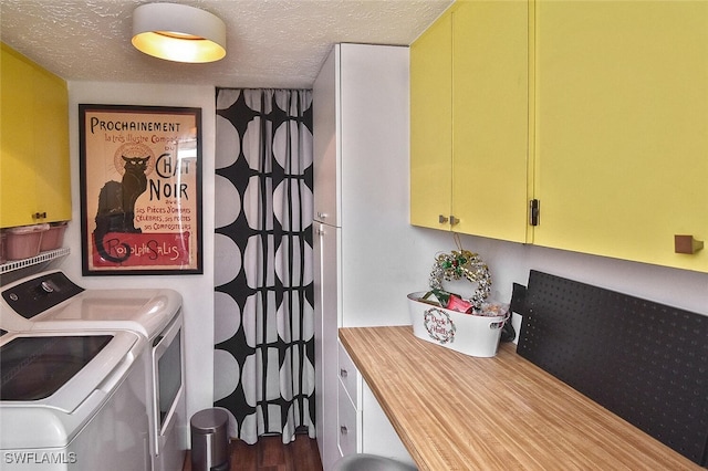 laundry area featuring a textured ceiling, dark hardwood / wood-style flooring, cabinets, and washing machine and dryer