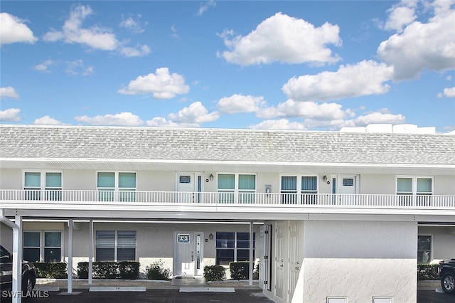 townhome / multi-family property featuring stucco siding, a shingled roof, and uncovered parking