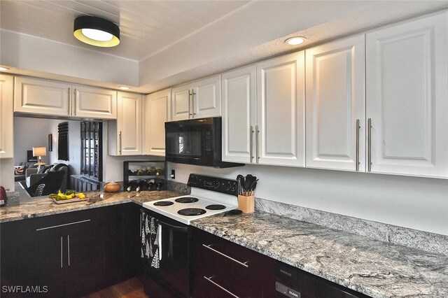 kitchen featuring black microwave, electric stove, white cabinetry, and light stone counters