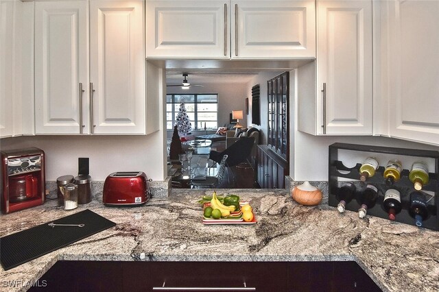 kitchen with ceiling fan, white cabinetry, and light stone counters