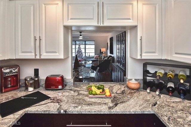 kitchen with white cabinetry, a ceiling fan, and light stone counters