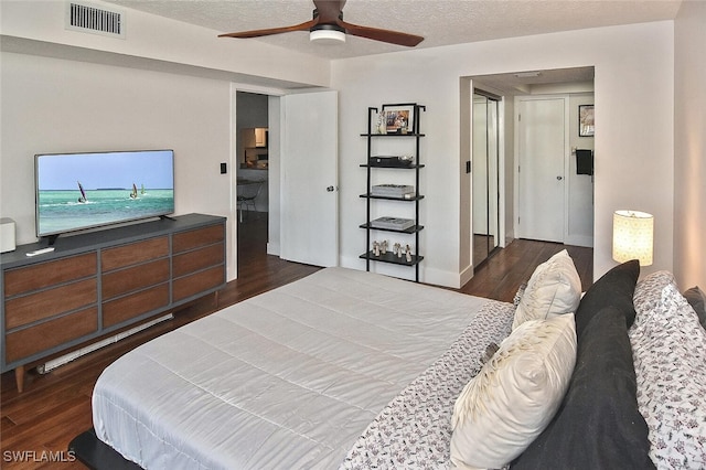 bedroom with ceiling fan, dark hardwood / wood-style flooring, and a textured ceiling