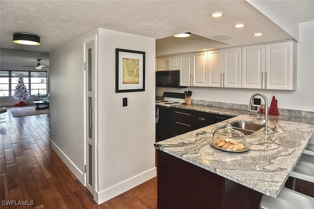 kitchen featuring sink, white cabinetry, a kitchen breakfast bar, kitchen peninsula, and dark hardwood / wood-style flooring