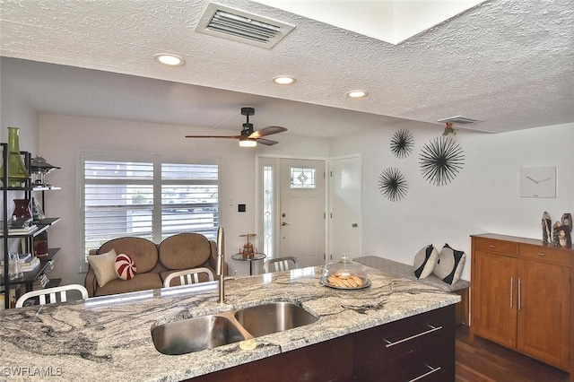 kitchen with sink, dark hardwood / wood-style floors, light stone countertops, and a textured ceiling