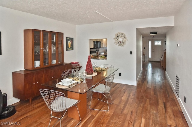 dining room featuring a textured ceiling and dark wood-type flooring