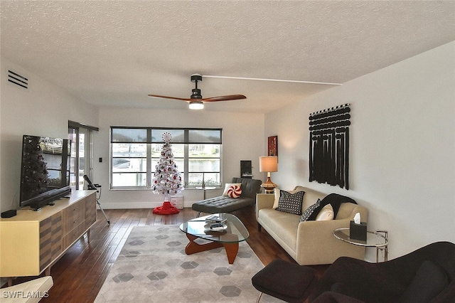 living room featuring a textured ceiling, dark hardwood / wood-style flooring, and ceiling fan