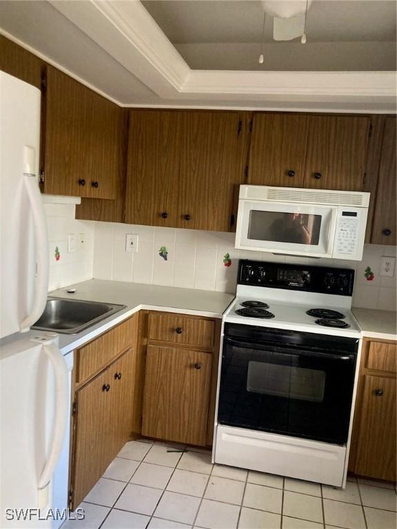 kitchen featuring tasteful backsplash, sink, light tile patterned floors, and white appliances