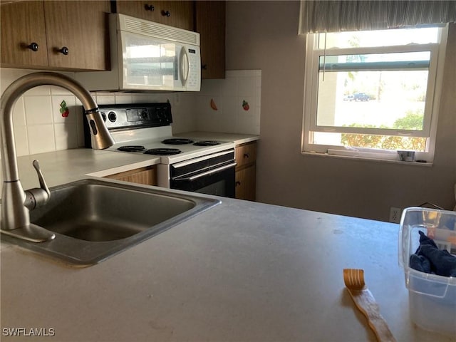 kitchen featuring sink, white appliances, and backsplash