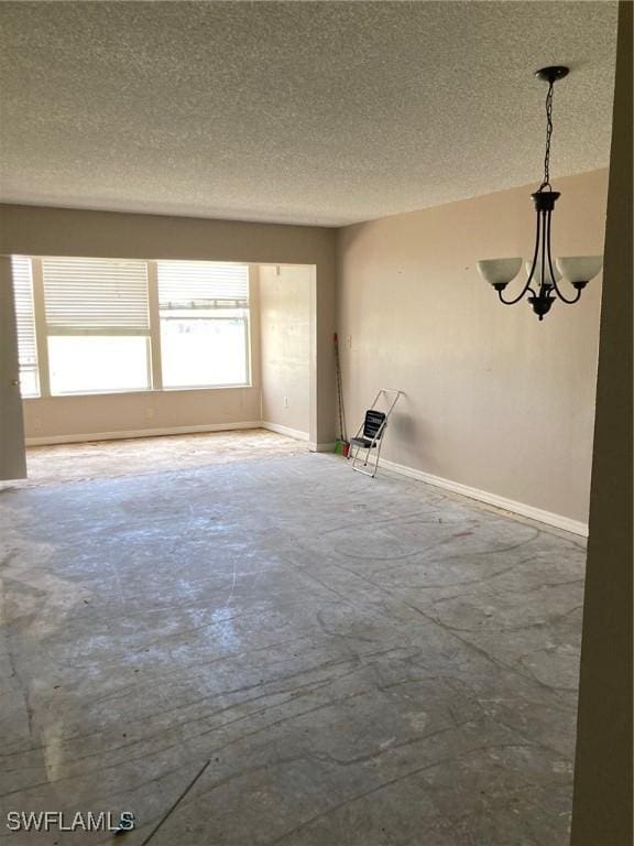 spare room with a textured ceiling and a notable chandelier